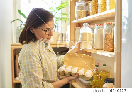 Woman in pantry taking products, eggs. Food storage, cooking at home 69407274