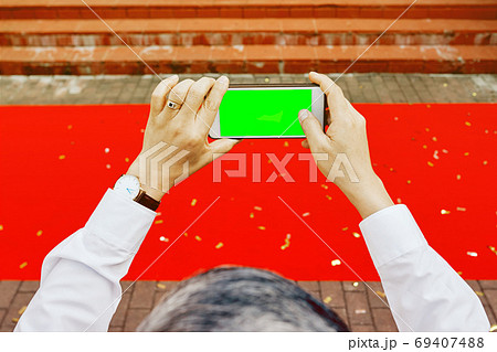 Man's hands shooting with phone empty green screen red carpet  69407488