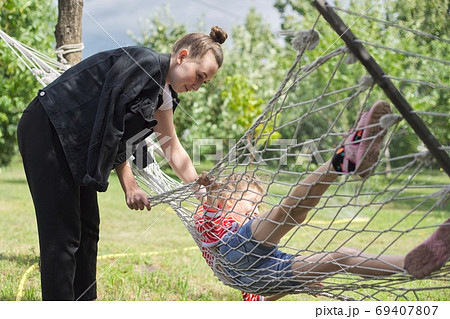 Teen sister girls and child having fun on hammock in the backyard garden 69407807