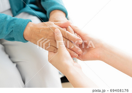 車椅子に座ったシニアの手を握る介護士 69408176