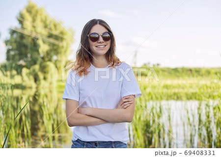 Portrait of smiling teenage girl in sunglasses on nature Portrait of smiling teenage girl in sunglasses on nature 69408331