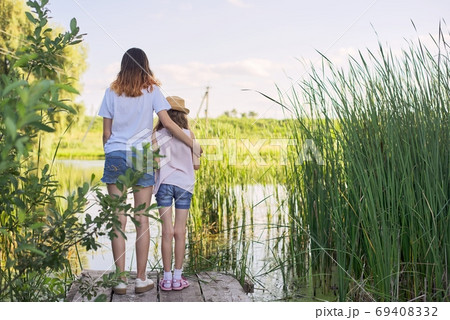 Children resting near the water on sunny summer day, back view 69408332