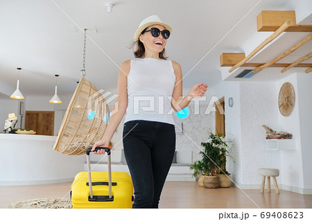 Mature beautiful woman with suitcase in lobby of modern spa resort hotel 69408623