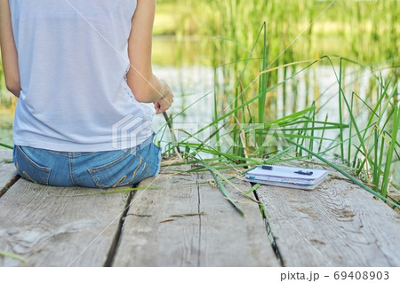 Young woman sitting with her back on wooden pier, copy space Young woman sitting with her back on wooden pier, copy space 69408903