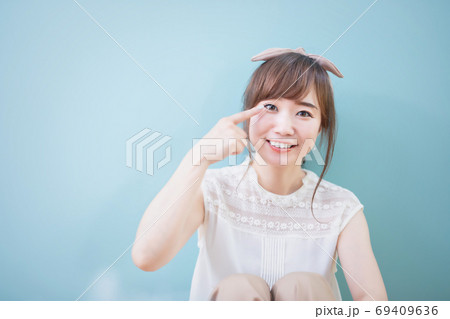 目元を指さす女性 69409636