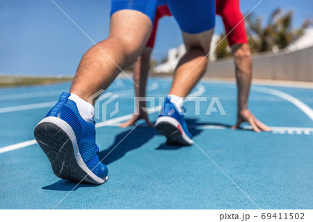 Sprinter waiting for start of race on running tracks at outdoor stadium. Sport and fitness runner man athlete on blue run track with running shoes. 69411502