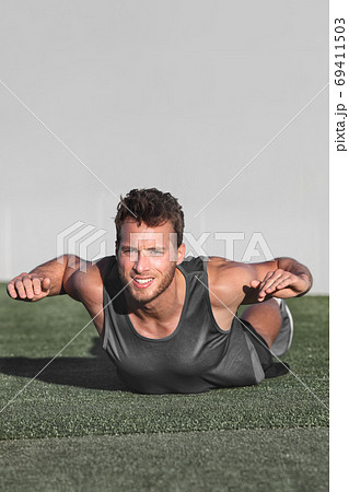 Lower back exercises for strengthening the muscles for spine health. Fitness man doing superman exercise workout with arms raised on gym floor. Bodyweight training. Lower back exercises for strengthening the muscles for spine health. Fitness man doing superman exercise workout with arms raised on gym floor. Bodyweight training. 69411503