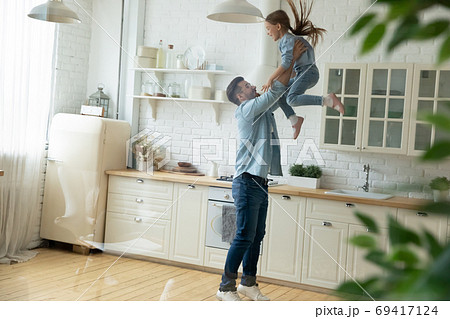 Happy young man lifting in air small preschool child daughter. Happy young man lifting in air small preschool child daughter. 69417124