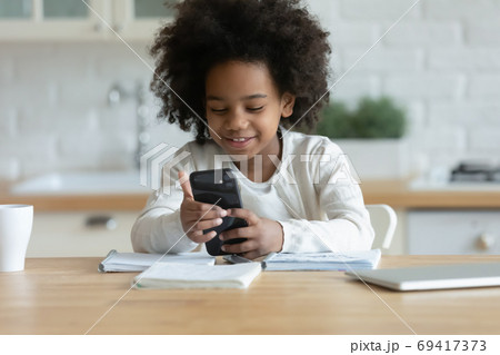 Happy small african ethnicity biracial child involved in mobile game. Happy small african ethnicity biracial child involved in mobile game. 69417373
