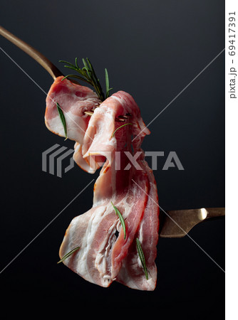 Bacon slices and rosemary on a fork. 69417391