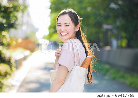 街中でエコバックを持つ笑顔の若い女性 69417769