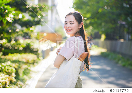 街中でエコバックを持つ笑顔の若い女性 69417776