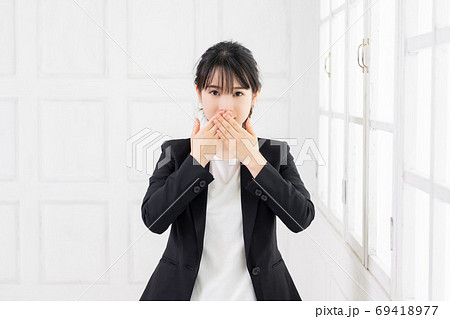 口を隠す若いビジネスウーマンの写真素材