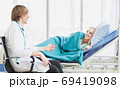 A doctor happily talks with a patient lying in bed 69419098