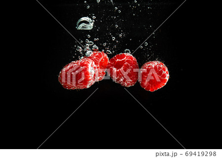 Raspberries splashing into clear water isolated on black background. Raspberries splashing into clear water isolated on black background. 69419298