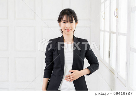 お腹に手を当てる若いビジネスウーマン お腹に手を当てる若いビジネスウーマン 69419337