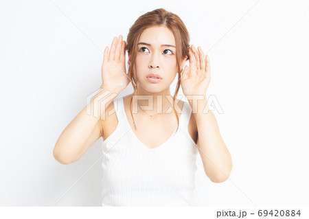 耳を澄ます若い女性 69420884