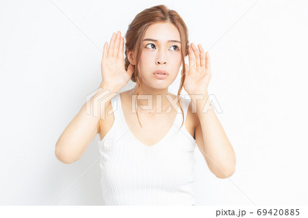 耳を澄ます若い女性 69420885