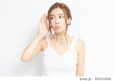 耳を澄ます若い女性 69420886