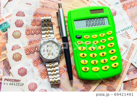 Against the background of Russian five-thousandth bills lies a calculator with the number one million, a watch and a pen Against the background of Russian five-thousandth bills lies a calculator with the number one million, a watch and a pen 69421491