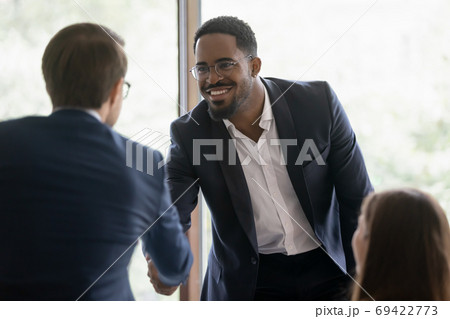 Smiling diverse businessmen handshake at meeting in office 69422773