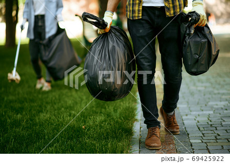 Man holds plastic trash bags in park, volunteering 69425922