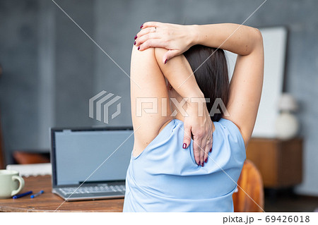 woman stretches her body after hard worling day. Rear view woman stretches her body after hard worling day. Rear view 69426018