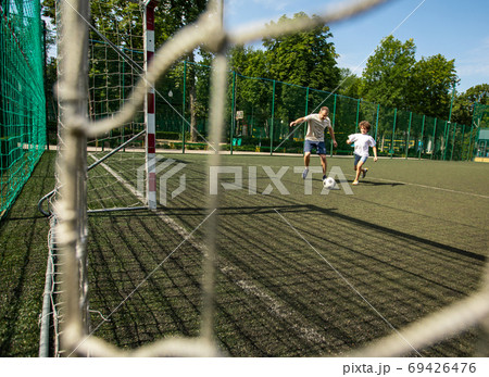 Sportive man playing football with little boy Sportive man playing football with little boy 69426476