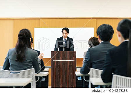 苦しい表情で講演をする男性 69427388