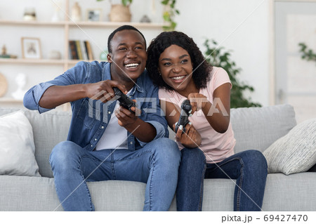 Joyful black man and woman with joysticks at home Joyful black man and woman with joysticks at home 69427470