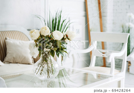 peonies in a vase on the table in a room with a 69428264