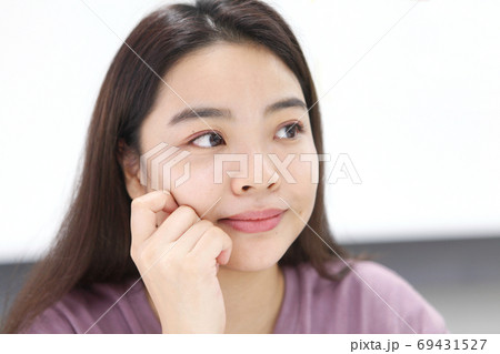 頬杖をつき微笑んで見つめる若い女性の写真素材