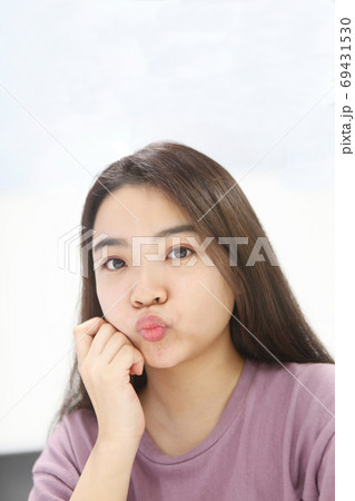 唇を尖らせて見つめる若い女性 69431530