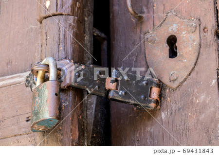 Close up of padlock and old hasp on an old wooden door. Locked old door with a cobweb. Close up of padlock and old hasp on an old wooden door. Locked old door with a cobweb. 69431843