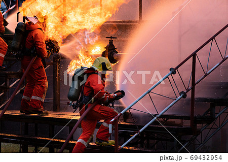 Firefighter team using water fog spraying down fire from oil rig 69432954
