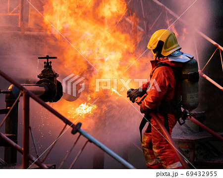 Firefighters using water fog spraying down fire from oil rig fac Firefighters using water fog spraying down fire from oil rig fac 69432955