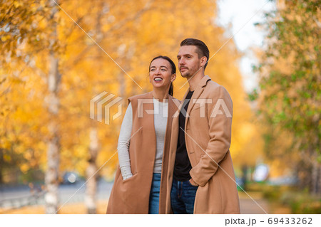 Happy family walking in autumn park on sunny fall day 69433262
