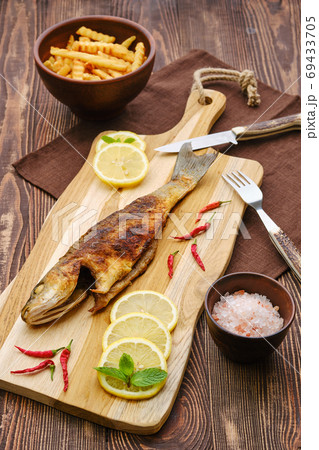 Fried sea bass with fried potato on wooden cutting board Fried sea bass with fried potato on wooden cutting board 69433705