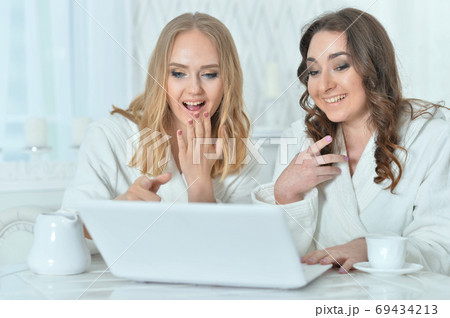 Portrait of young women in bathrobes with laptop 69434213