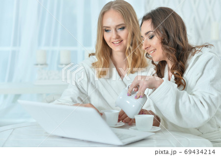 Portrait of young women in bathrobes with laptop 69434214