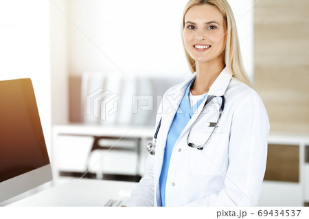 Woman-doctor controls medication history records and exam results while using laptop computer in sunny hospital. Medicine and healthcare concept Woman-doctor controls medication history records and exam results while using laptop computer in sunny hospital. Medicine and healthcare concept 69434537