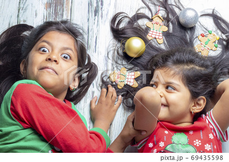 Smiling sisters decorating their hair with Christmas decorations Smiling sisters decorating their hair with Christmas decorations 69435598