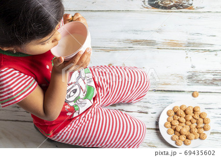 Cute little girl is playing with Santa's cookies and milk at Chr Cute little girl is playing with Santa's cookies and milk at Chr 69435602