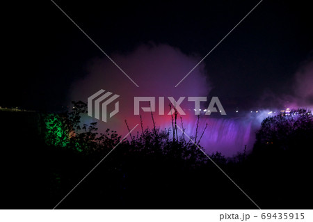 NIAGARA FALLS, ONTARIO, CANADA - MAY 21st 2018: Niagara Falls illuminates the falls at night on the Canadian and American sides NIAGARA FALLS, ONTARIO, CANADA - MAY 21st 2018: Niagara Falls illuminates the falls at night on the Canadian and American sides 69435915