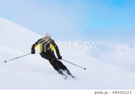Alpine skier on piste running downhill Alpine skier on piste running downhill 69436223