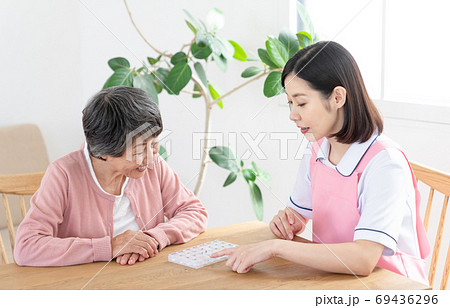 薬ケースの説明をする介護士 69436296