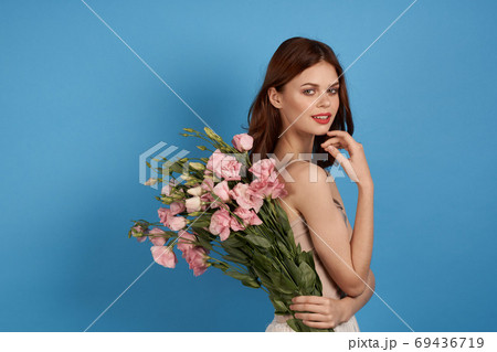 Beautiful woman with a bouquet of pink flowers on a blue background spring model  69436719
