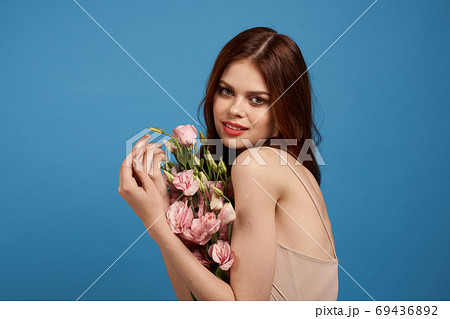 Beautiful woman with a bouquet of pink flowers on a blue background spring model Beautiful woman with a bouquet of pink flowers on a blue background spring model 69436892