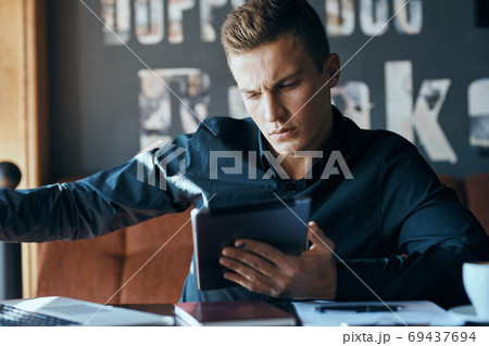 Business man freelancer with laptop in cafe at the table manager documents cup of coffee model Business man freelancer with laptop in cafe at the table manager documents cup of coffee model 69437694