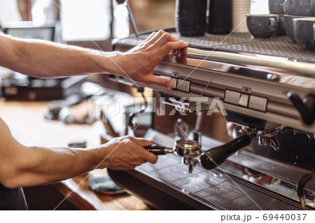 coffee shop owner is turning the coffeemaker on 69440037